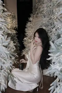 Christmas Muse: Elegant Beauty in a Backless Satin Dress by a Sparkling Tree - image 1