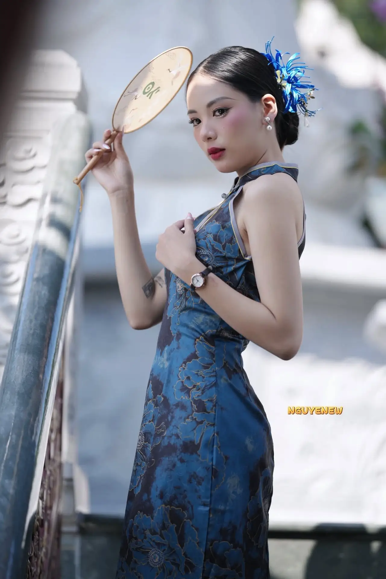 Captivating Asian Beauty: Elegant Woman in Blue Cheongsam with Traditional Fan