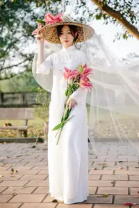 Discover the captivating grace of a Vietnamese woman in a flowing white Ao Dai and traditional conical hat - image 2