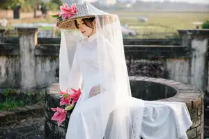 Discover the captivating grace of a Vietnamese woman in a flowing white Ao Dai and traditional conical hat - image 0