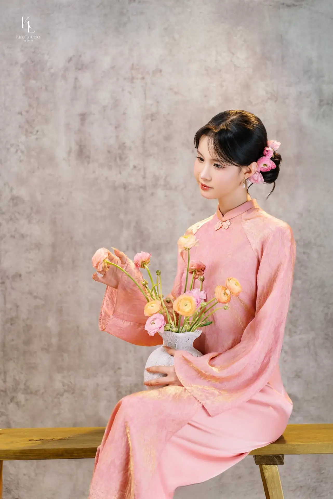 Elegant Asian Charm: Serene Young Woman in Traditional Pink Attire with Delicate Fresh Flowers