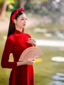 Discover the enchanting beauty of a Vietnamese woman in a traditional Red Ao Dai by the tranquil water. - image 2