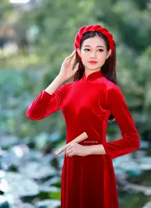 Discover the enchanting beauty of a Vietnamese woman in a traditional Red Ao Dai by the tranquil water. - image 0