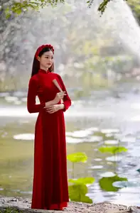 Discover the enchanting beauty of a Vietnamese woman in a traditional Red Ao Dai by the tranquil water. - image 3