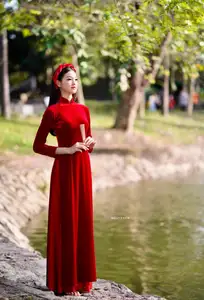 Discover the enchanting beauty of a Vietnamese woman in a traditional Red Ao Dai by the tranquil water. - image 7
