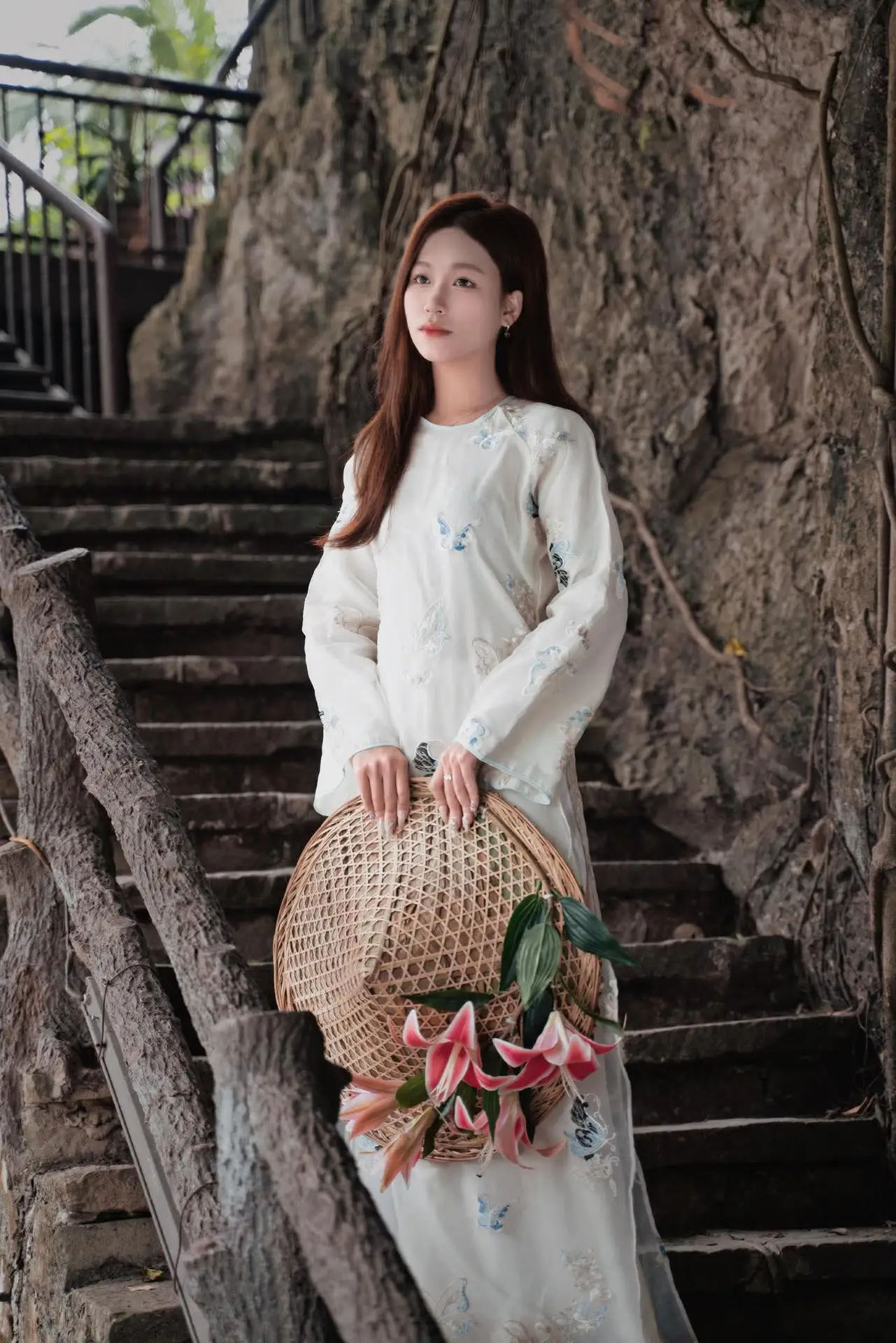 Elegant Vietnamese Beauty in White Ao Dai Serene Portrait with Pink Lilies on Ancient Stone Steps